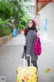 A woman with a pink backpack and a yellow suitcase.