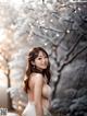 A woman in a white dress standing in front of a tree.