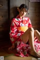 A woman in a red kimono sitting on the floor.