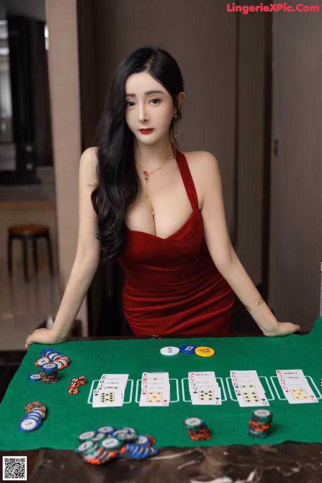 A woman in a red dress sitting at a poker table.