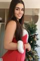 A woman in a red dress standing next to a Christmas tree.