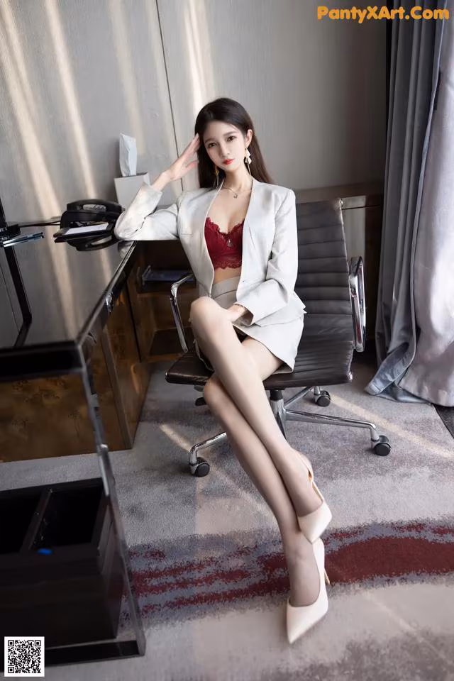 A woman sitting on a chair in front of a desk.