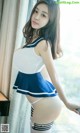 A woman in a sailor outfit posing by a window.