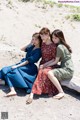 A group of three women sitting on top of a log.