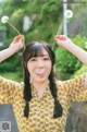 A woman in a yellow dress holding a dandelion in her hands.