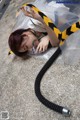 A woman laying on the ground with a hose attached to her head.