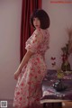 A woman in a pink dress standing next to a table.