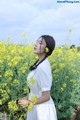 A woman standing in a field of yellow flowers.