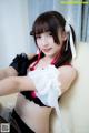 A woman in a maid outfit sitting on a couch.