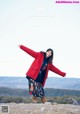 A woman standing on top of a mountain with her arms outstretched.