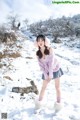 A woman in a pink sweater is standing in the snow.