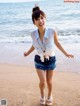 A woman standing on a beach with her arms outstretched.