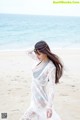 A woman in a white dress standing on a beach.