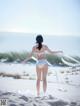 A woman in a white bikini standing on a beach.