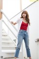 a woman in a red top and blue jeans posing for a picture