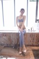 A woman sitting on a counter in a bathroom.