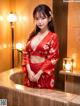 A woman in a red kimono posing in a bathroom.