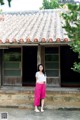 A woman standing in front of a building with a tiled roof.