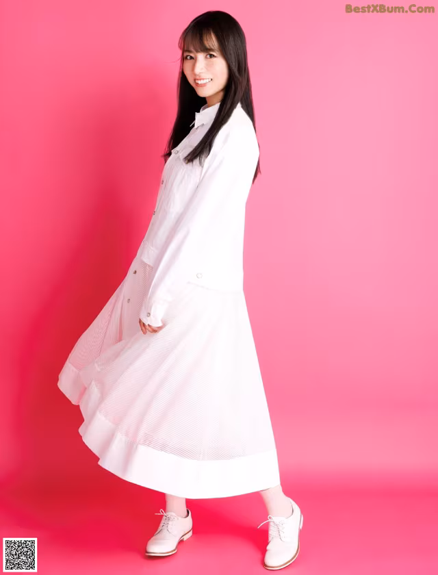 A woman in a white shirt and skirt posing for a picture.