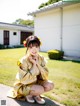 A woman in a yellow kimono sitting on the ground.