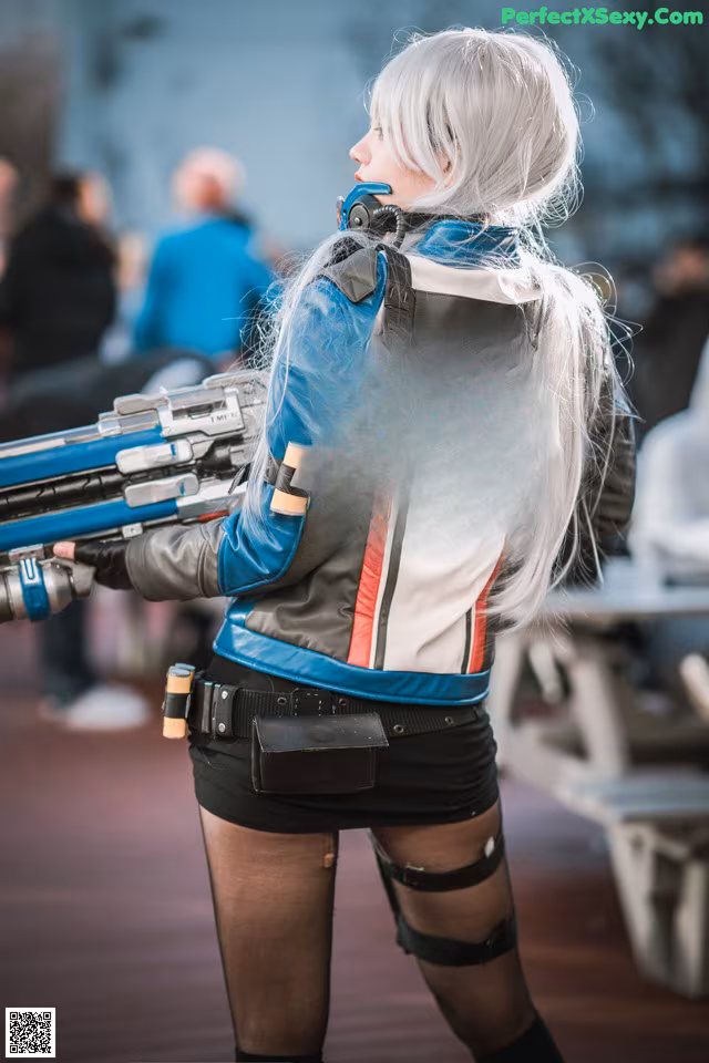 A woman in a leather jacket holding a gun.